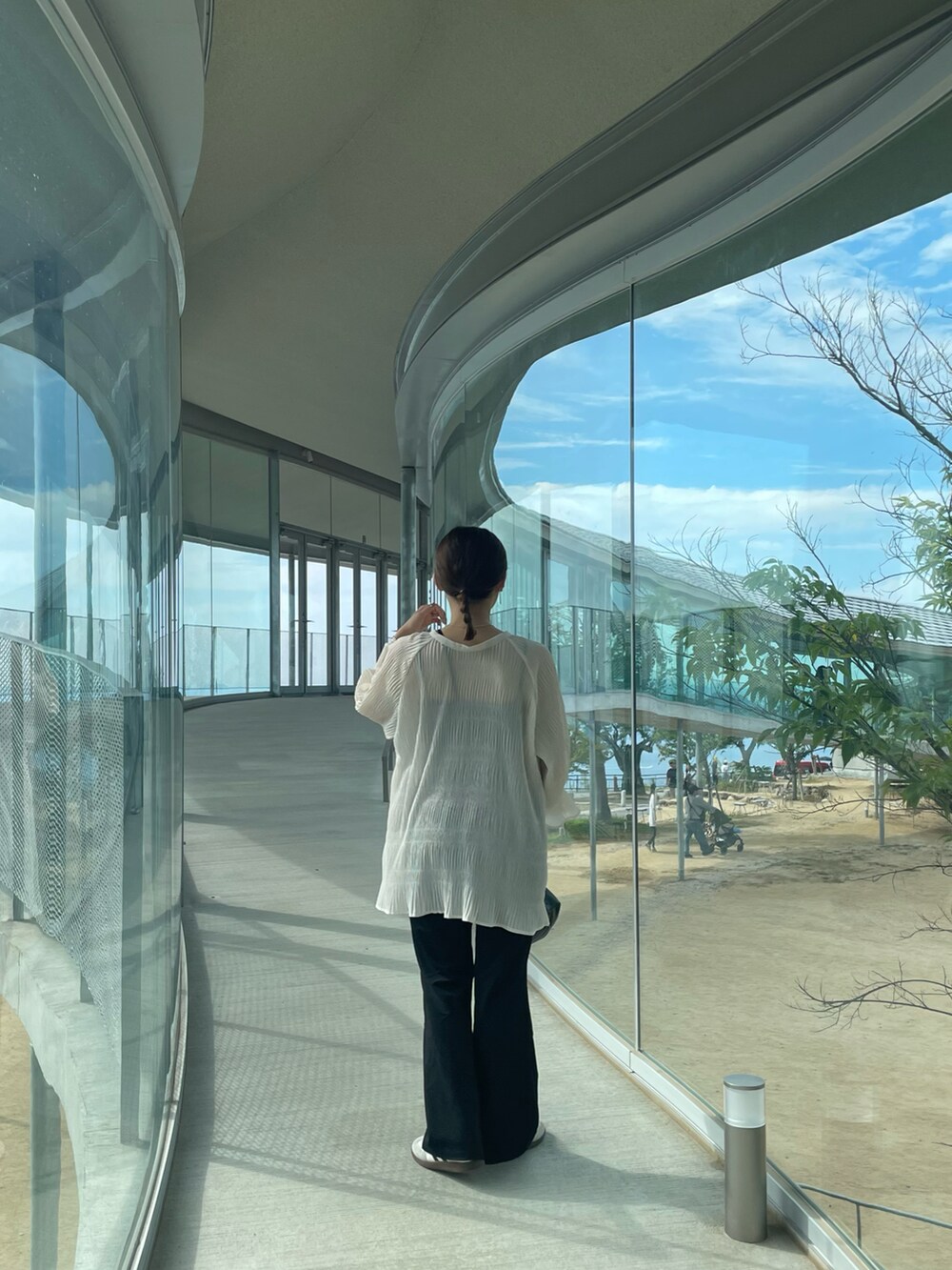 ホワイト系のトップス、ブラック系のパンツ、ブラック系のショルダーバッグを着用したレディースの夏コーディネートの3枚目の写真