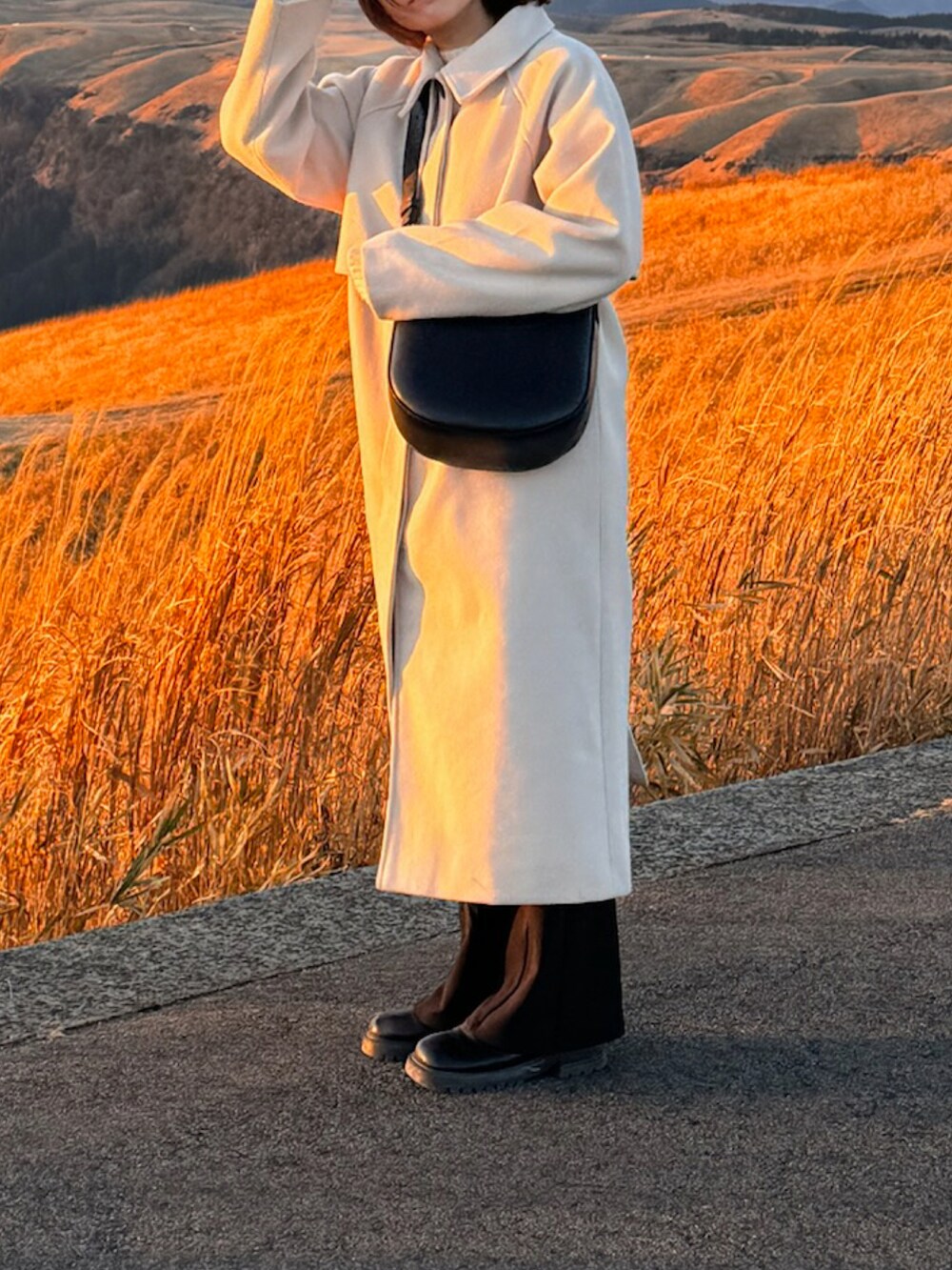 ブラック系のバッグ、ホワイト系のノーカラーコート、ブラック系のパンツを着用したレディースの冬コーディネートの2枚目の写真