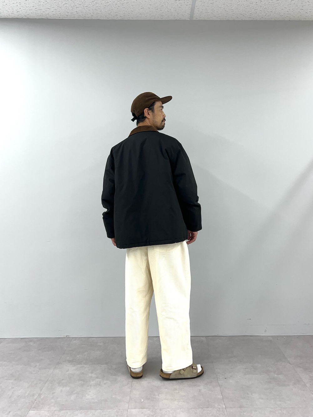 ブラック系のブルゾン、ホワイト系のチノパンツを着用したメンズの秋コーディネートの4枚目の写真