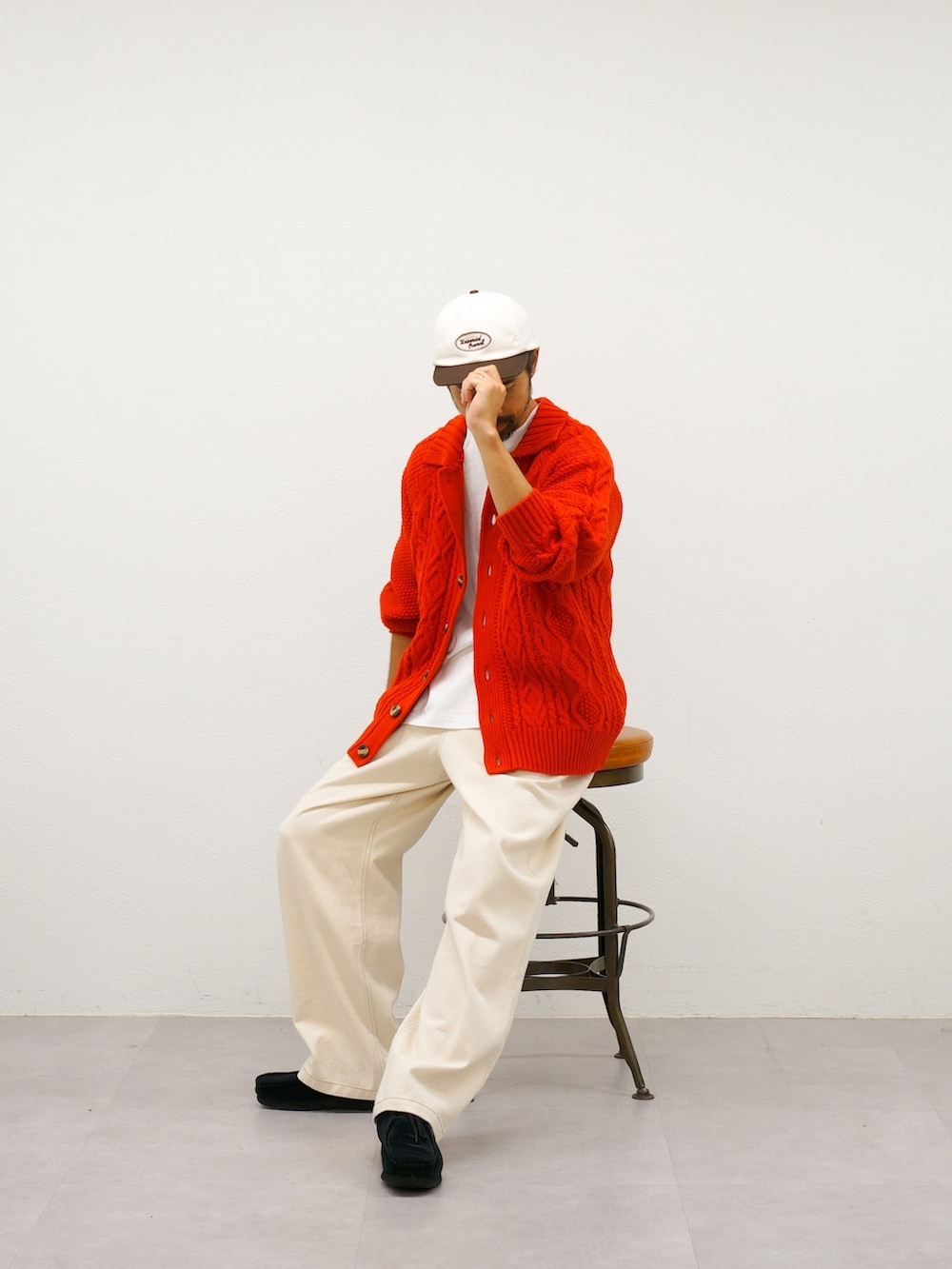 レッド系のカーディガン/ボレロ、ホワイト系のデニムパンツを着用したメンズの冬コーディネートの4枚目の写真