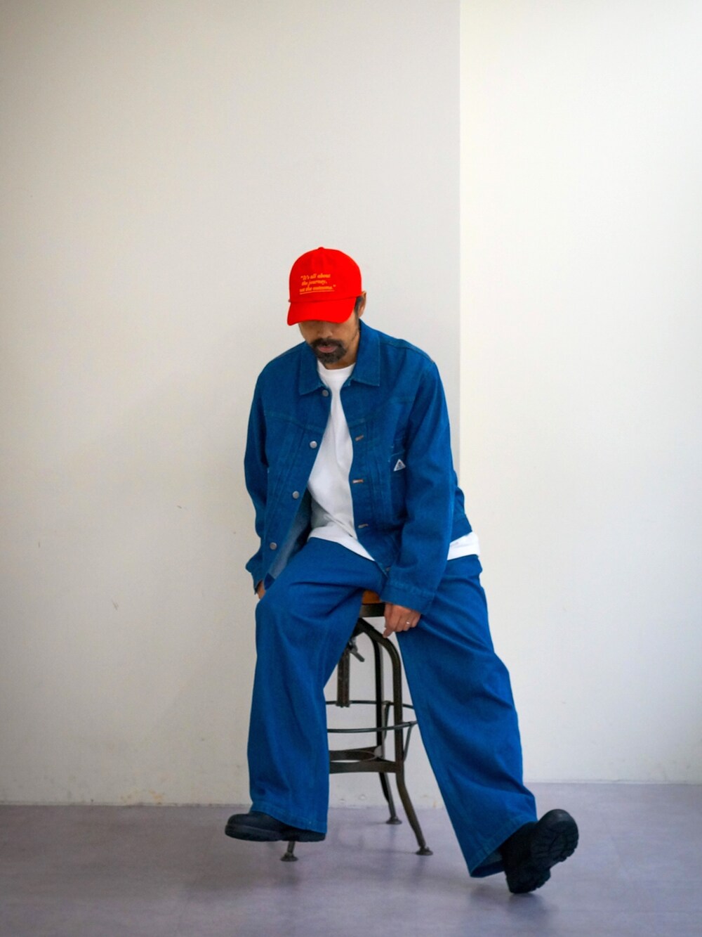 ブルー系のデニムジャケット、ブルー系のデニムパンツ、レッド系のキャップを着用したメンズの冬コーディネートの2枚目の写真