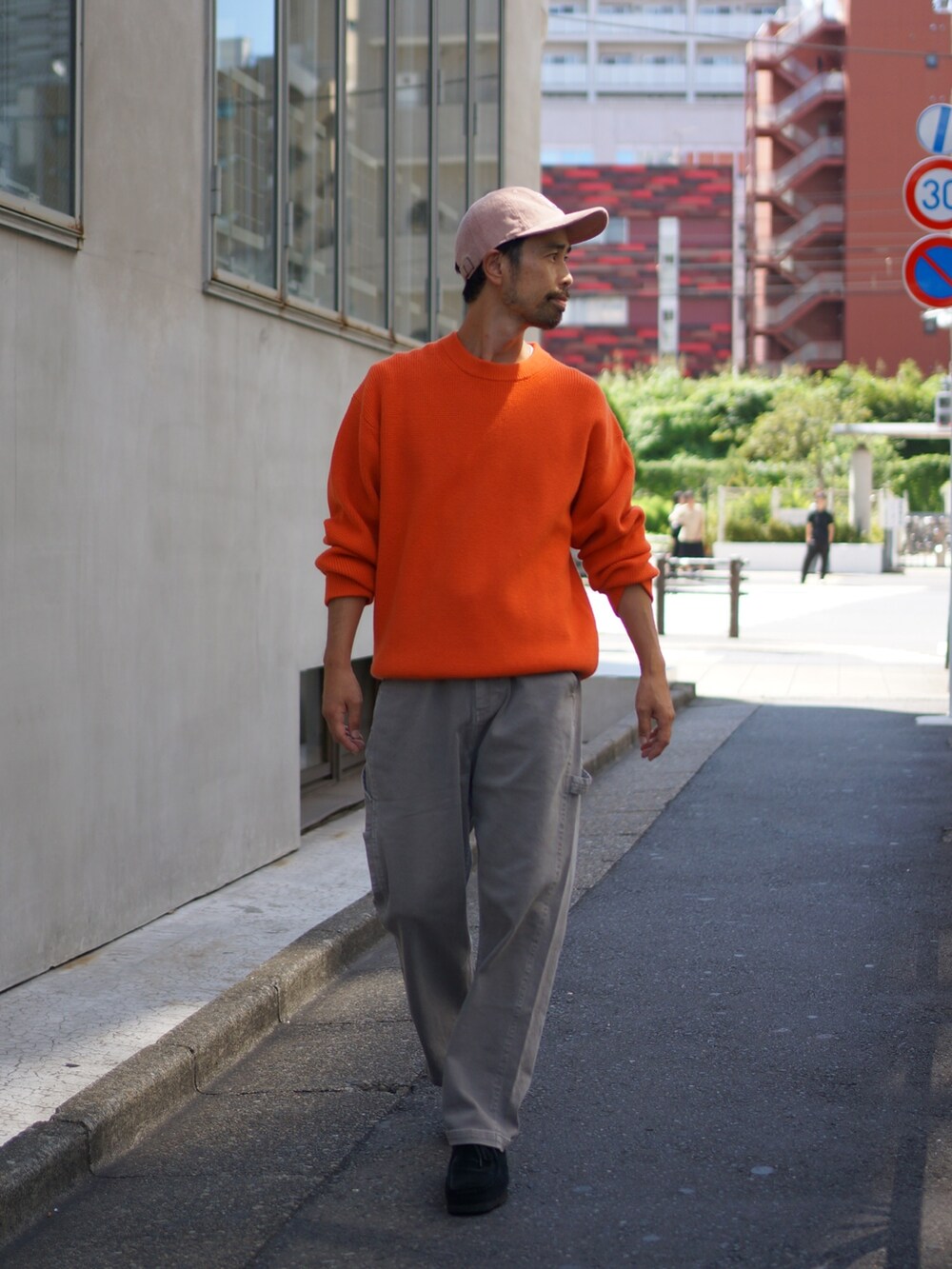 オレンジ系のニット/セーター、グレー系のデニムパンツ、ブラック系のブーツを着用したメンズの夏コーディネートの3枚目の写真