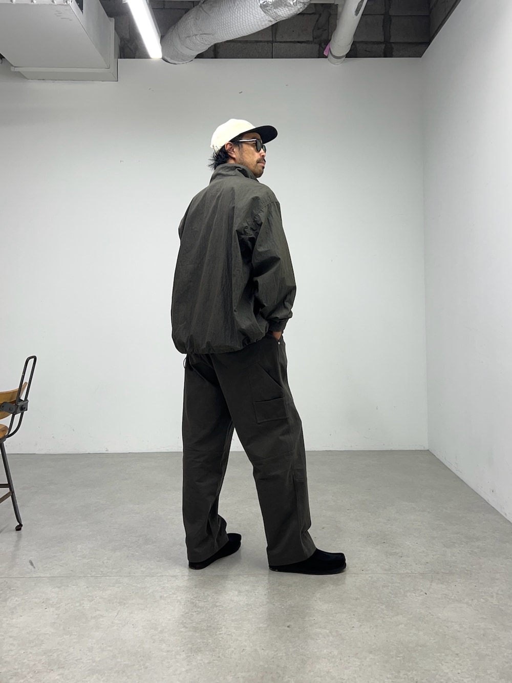 グレー系のナイロンジャケット、グレー系のパンツ、ベージュ系のキャップを着用したメンズの夏コーディネートの3枚目の写真