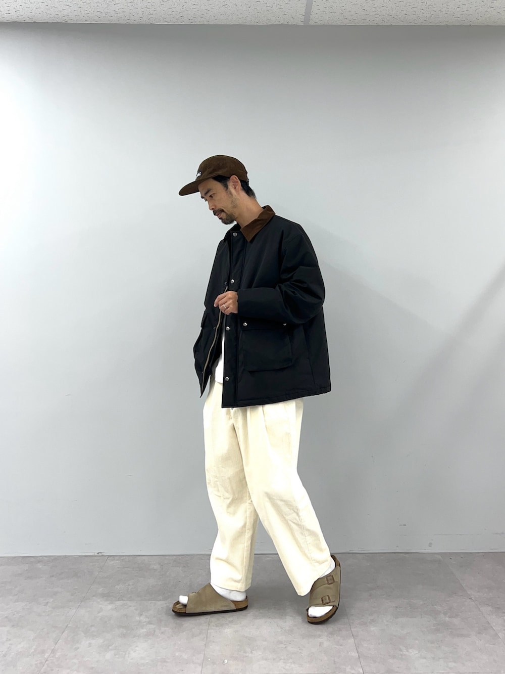 ブラック系のブルゾン、ホワイト系のチノパンツを着用したメンズの秋コーディネートの3枚目の写真