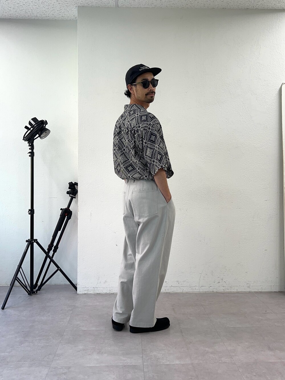 ブラック系のシャツ/ブラウス、グレー系のチノパンツ、ブラック系のキャップを着用したメンズの夏コーディネートの2枚目の写真