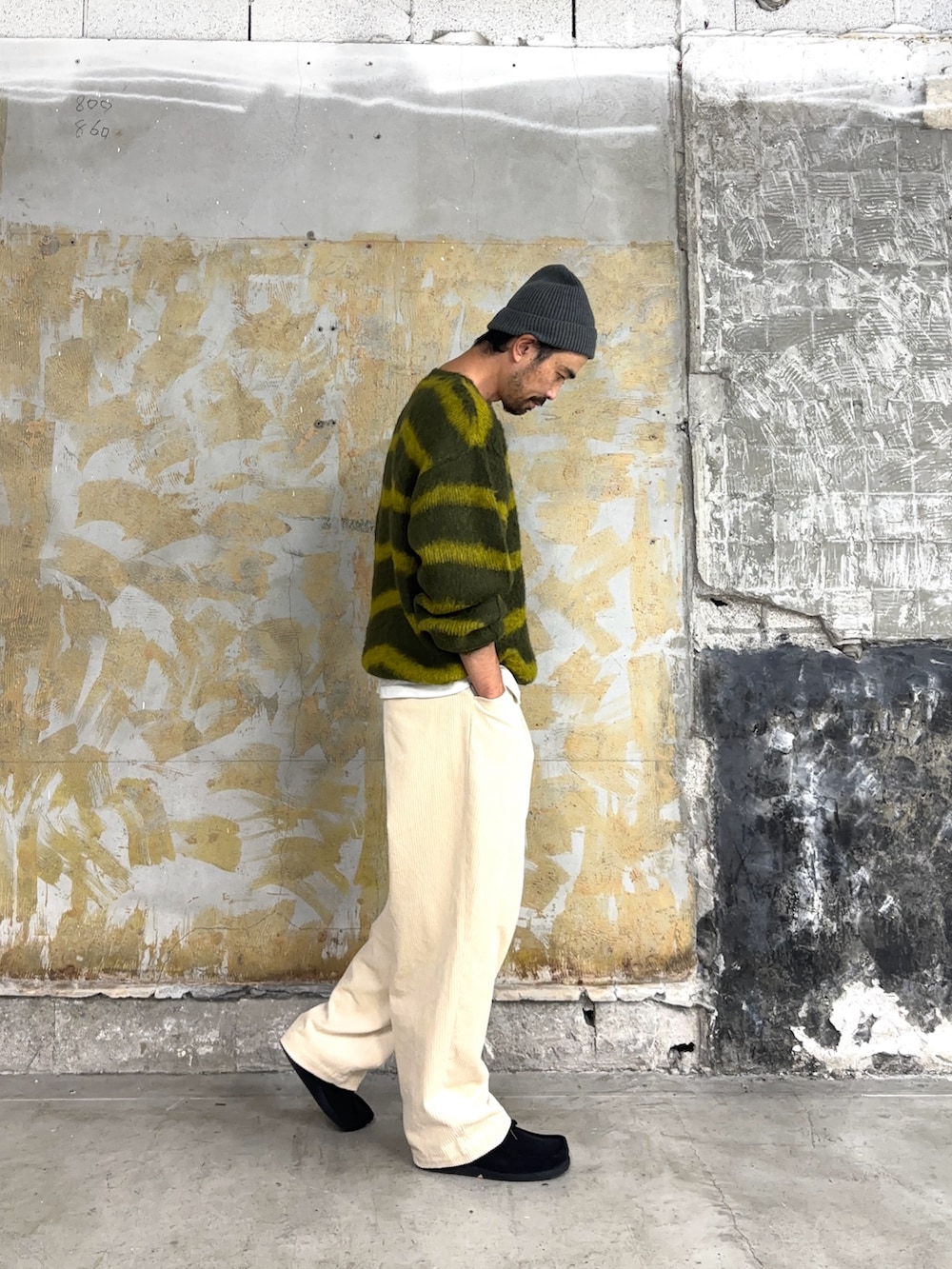 グリーン系のニット/セーター、グレー系のニットキャップ/ビーニーを着用したメンズの秋コーディネートの3枚目の写真