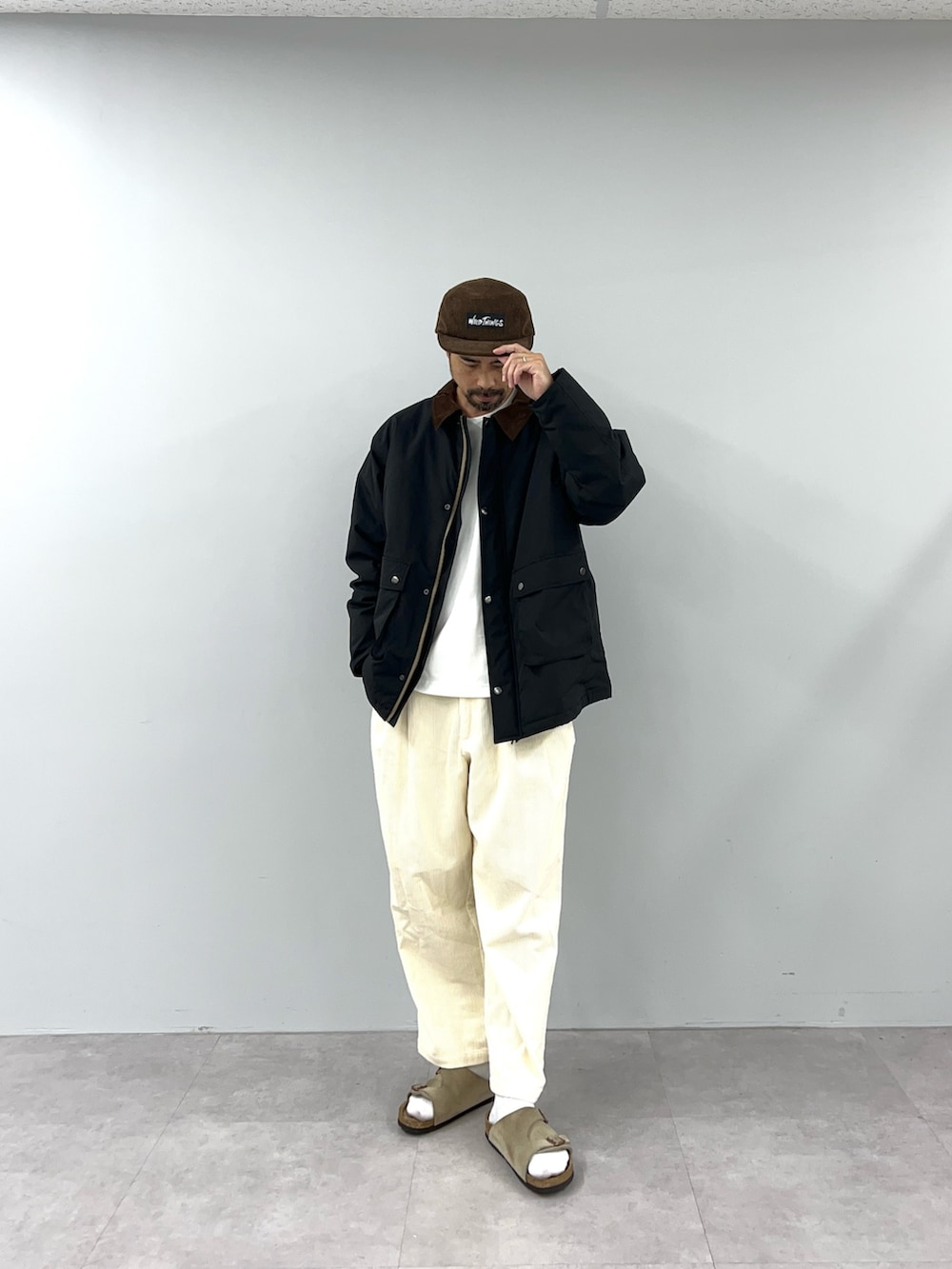ブラック系のブルゾン、ホワイト系のチノパンツを着用したメンズの秋コーディネートの2枚目の写真