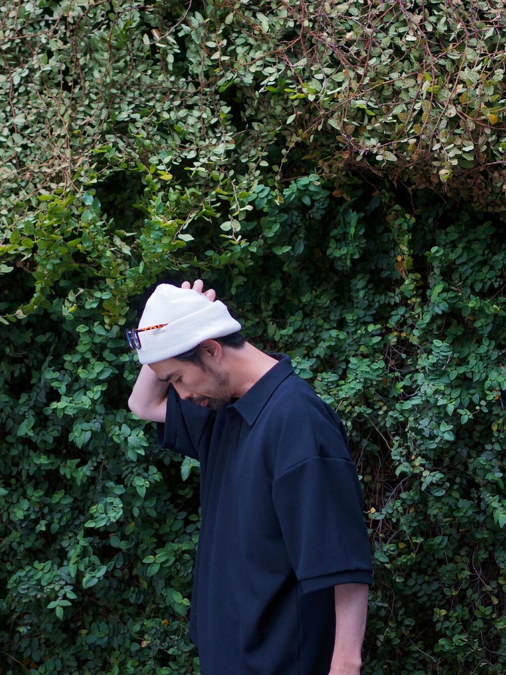 ブラック系のポロシャツ、ブラック系のブーツ、ホワイト系のトートバッグを着用したメンズの春コーディネートの3枚目の写真