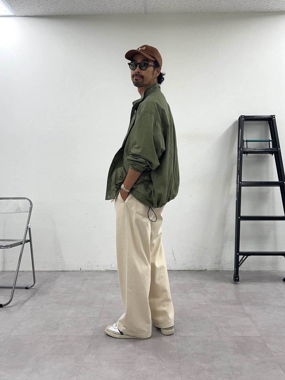 グリーン系のナイロンジャケットを着用したメンズの秋コーディネートの2枚目の写真