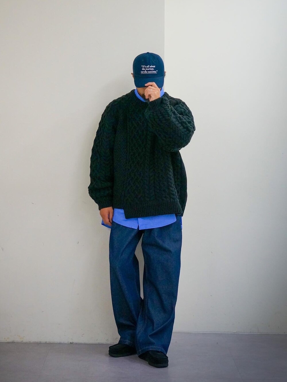 ブラック系のニット/セーター、ブルー系のデニムパンツ、ブルー系のキャップを着用したメンズの秋コーディネートの2枚目の写真