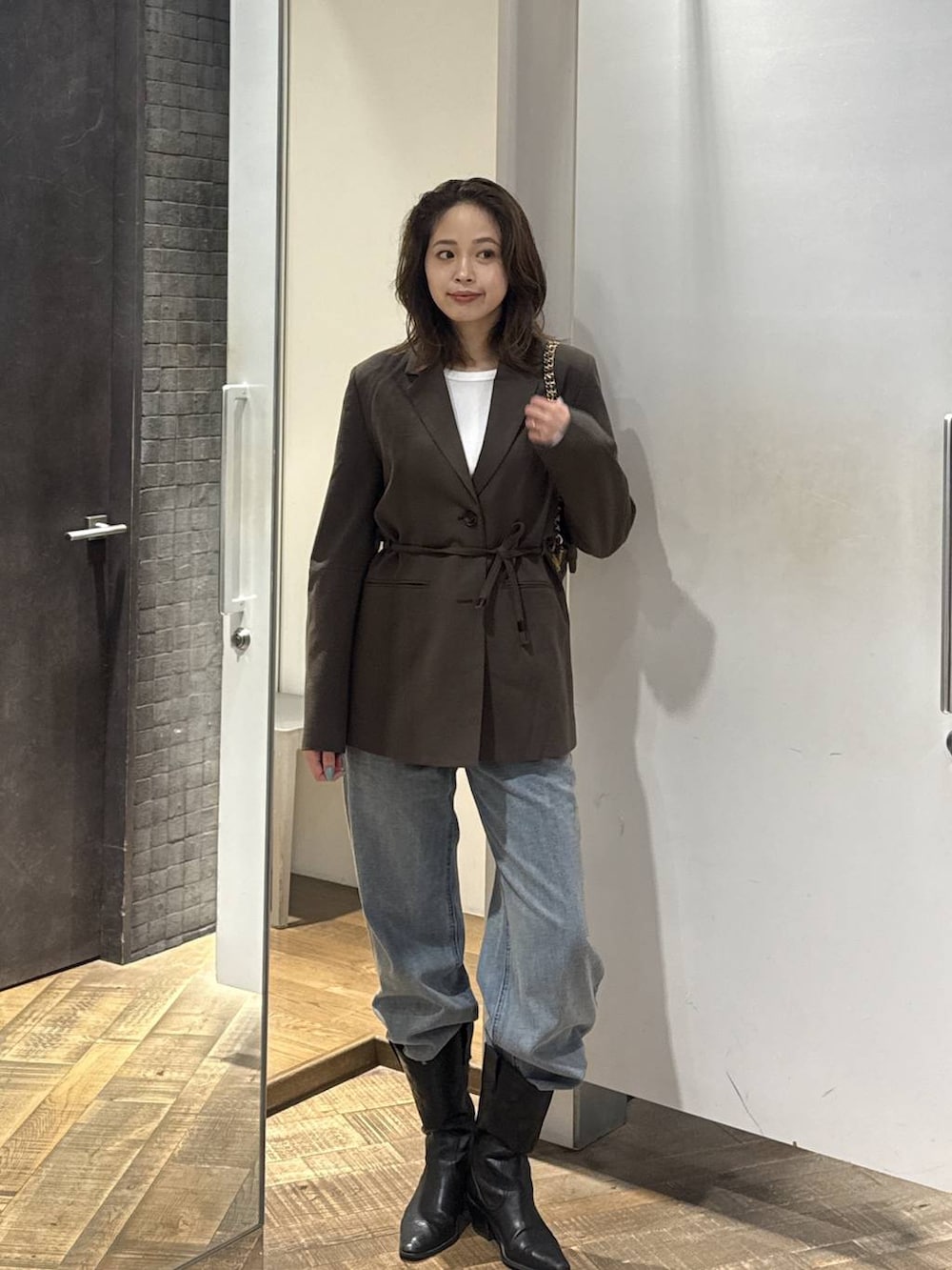 ブルー系のデニムパンツ、ブラウン系のテーラードジャケット、ホワイト系のTシャツ/カットソーを着用したレディースの秋コーディネートの2枚目の写真