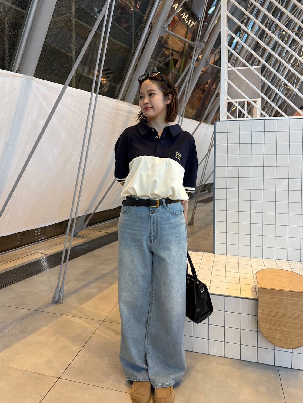 ベージュ系のローファー、ブラック系のボストンバッグ、ブルー系のデニムパンツを着用したレディースの春コーディネートの2枚目の写真