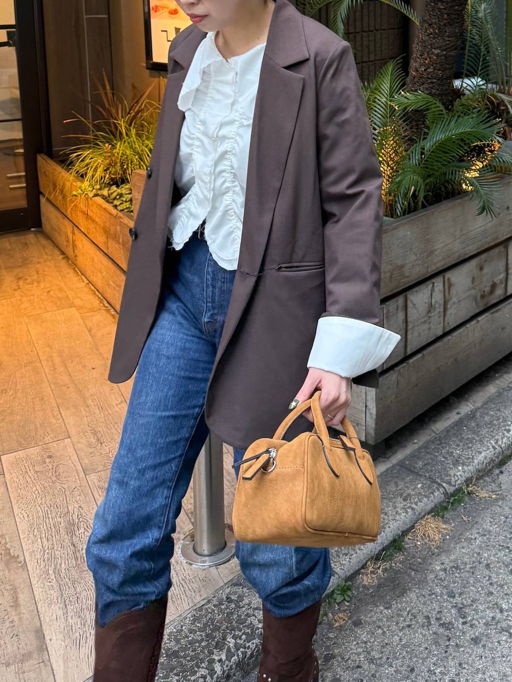 ブラウン系のテーラードジャケット、ブラウン系のボストンバッグ、ブラウン系のブーツを着用したレディースの春コーディネートの2枚目の写真