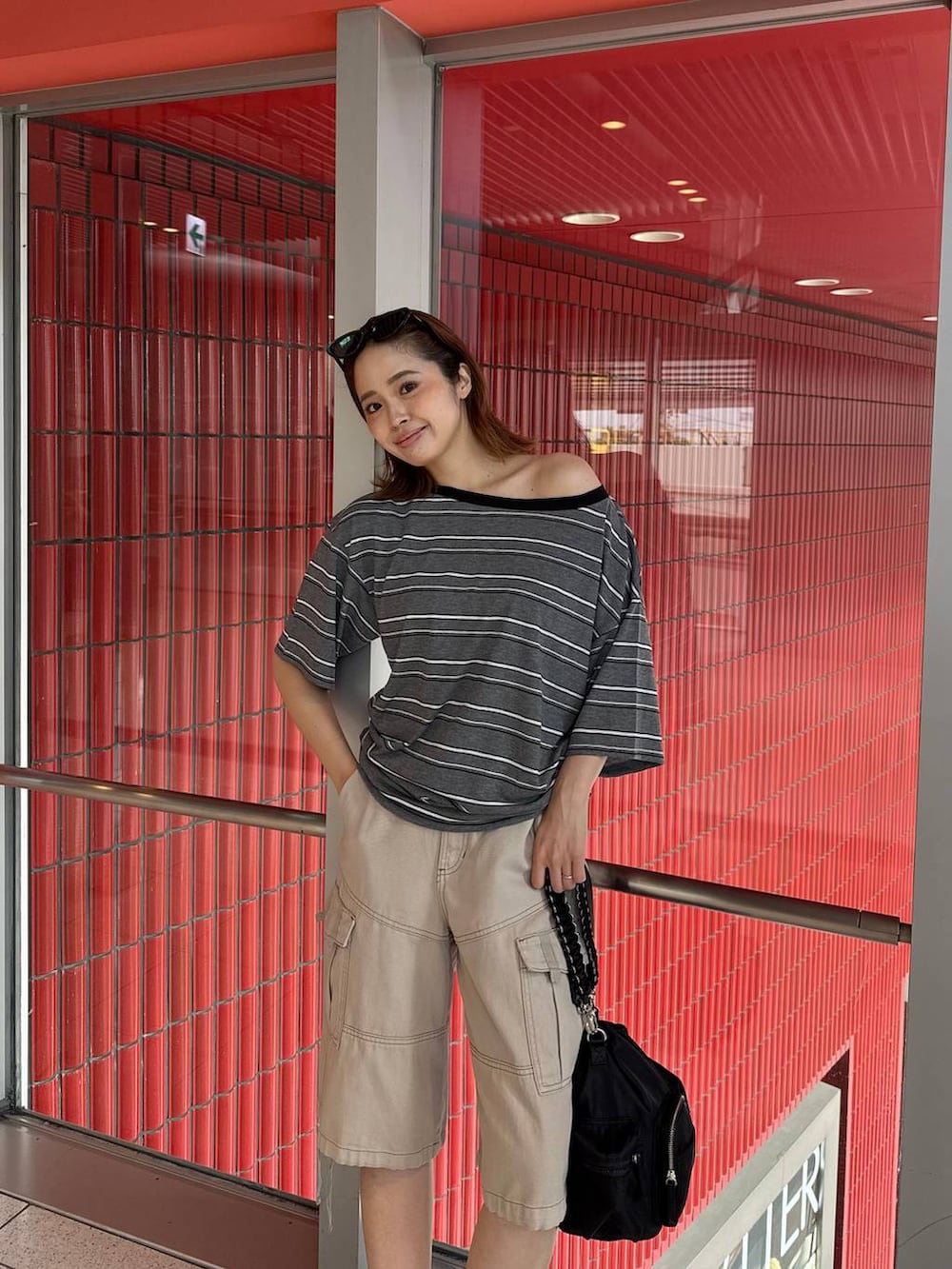 ブラック系のショルダーバッグ、グレー系のTシャツ/カットソー、ブラック系のパンプスを着用したレディースの夏コーディネートの3枚目の写真
