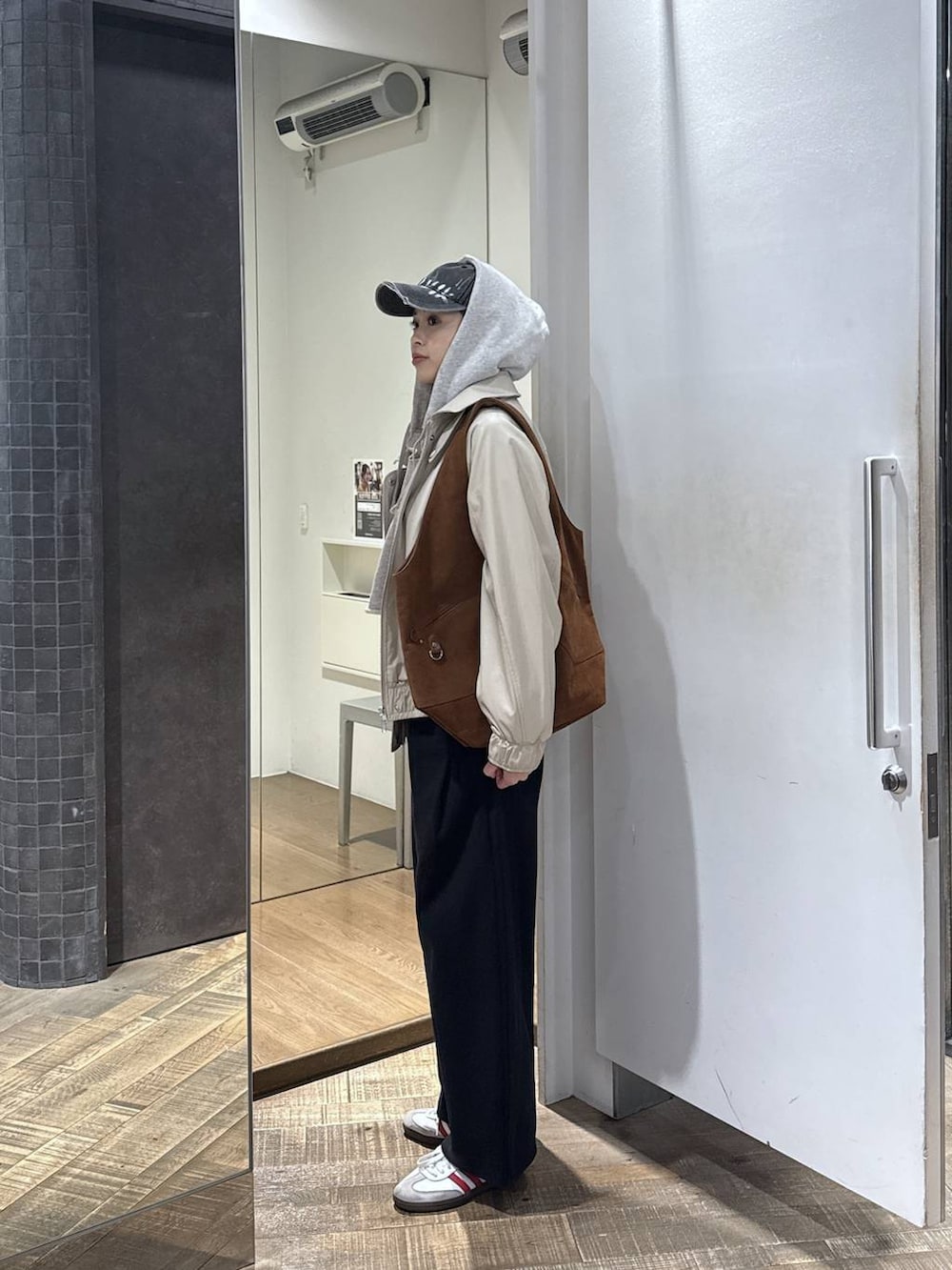 ブラウン系のトートバッグ、ベージュ系のブルゾン、グレー系のパーカーを着用したレディースの冬コーディネートの2枚目の写真