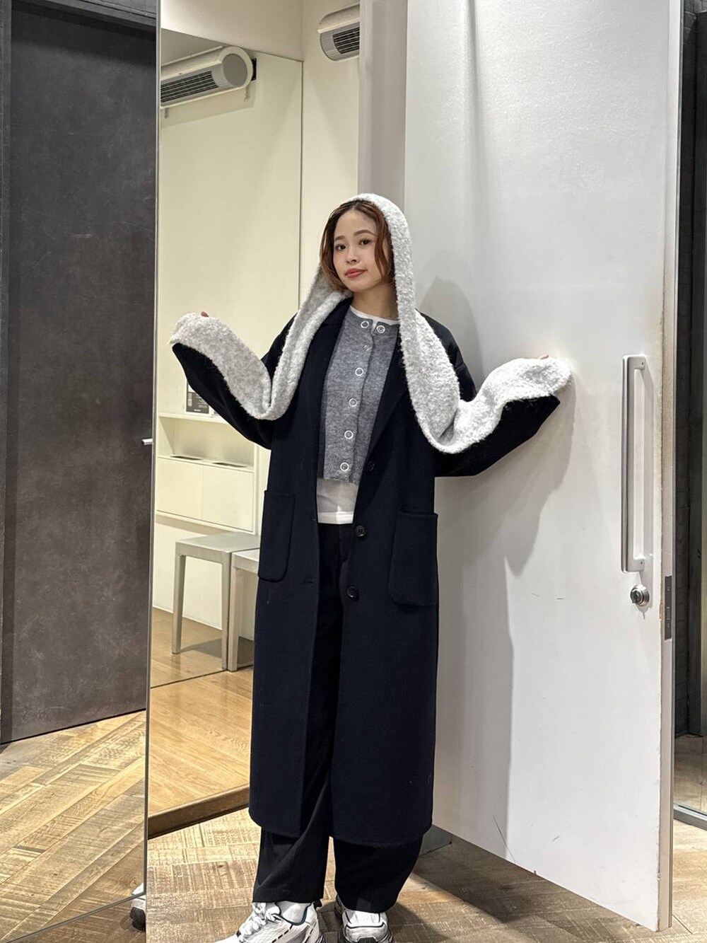 ブルー系のチェスターコート、ホワイト系のスニーカー、グレー系のカーディガン/ボレロを着用したレディースの秋コーディネートの2枚目の写真