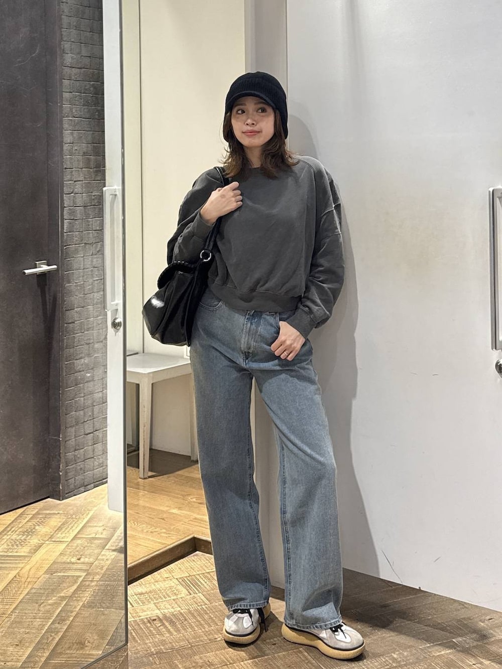 ブルー系のデニムパンツ、ブラック系のショルダーバッグ、グレー系のスウェットを着用したレディースの秋コーディネートの2枚目の写真