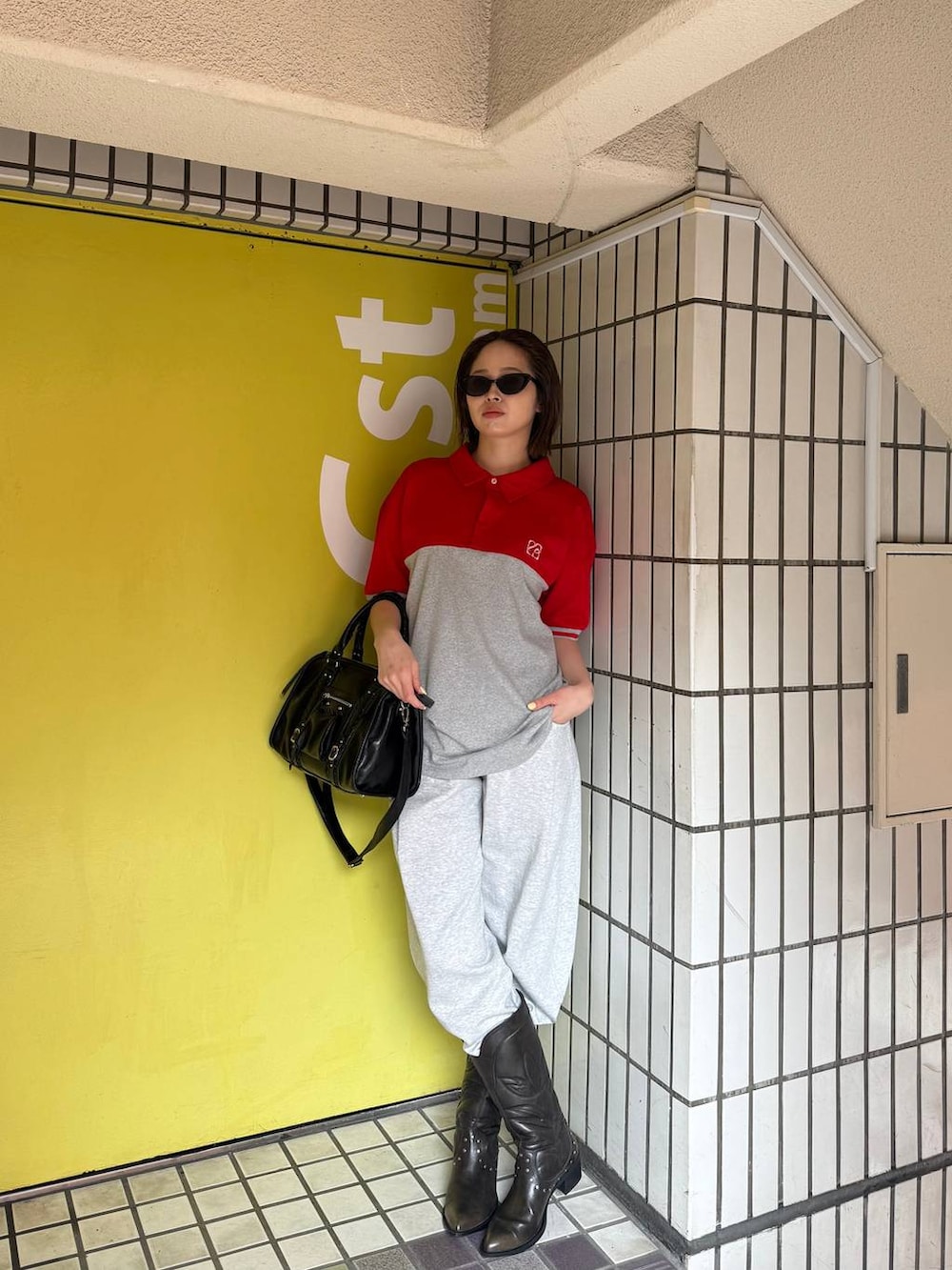 ブラック系のブーツ、ブラック系のボストンバッグ、グレー系のスウェットパンツを着用したレディースの春コーディネートの3枚目の写真