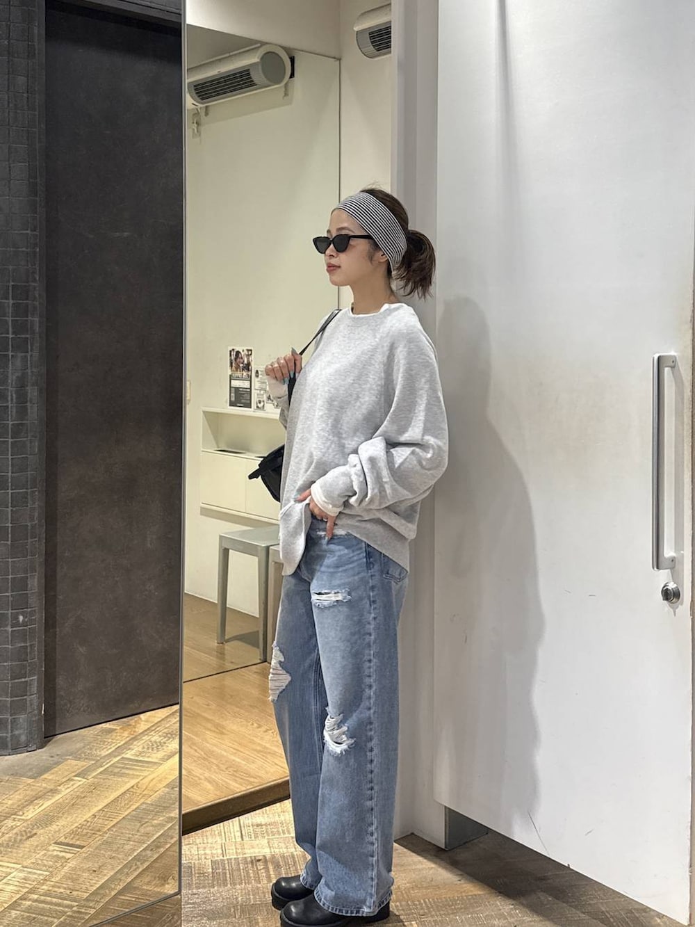 ブルー系のデニムパンツ、ブラック系のモカシン/デッキシューズ、グレー系のスウェットを着用したレディースの秋コーディネートの2枚目の写真