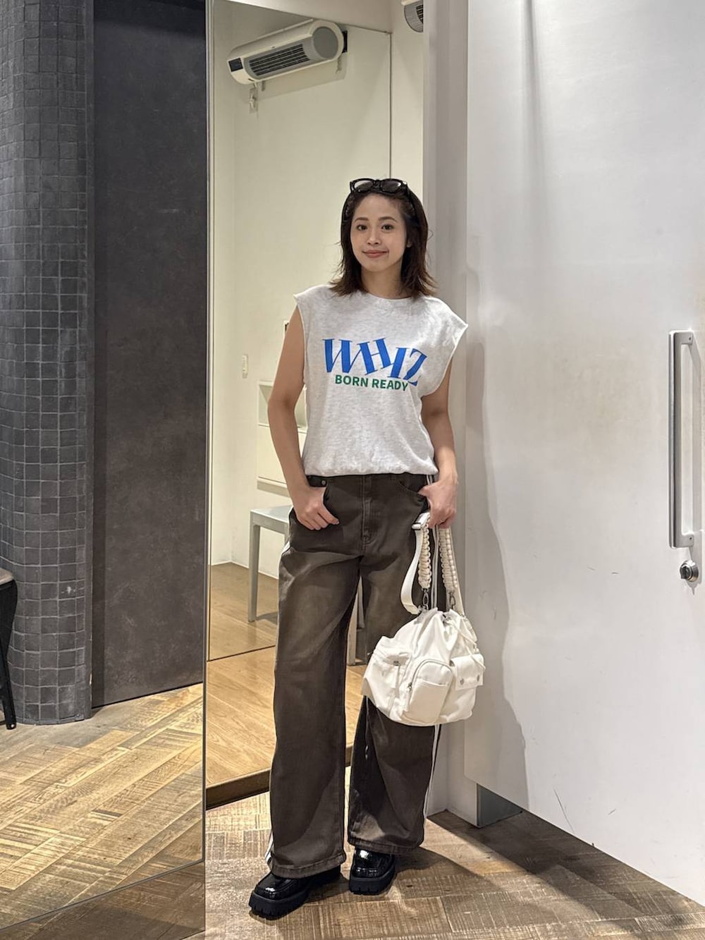 ホワイト系のショルダーバッグ、ブラック系のローファー、グレー系のTシャツ/カットソーを着用したレディースの夏コーディネートの3枚目の写真