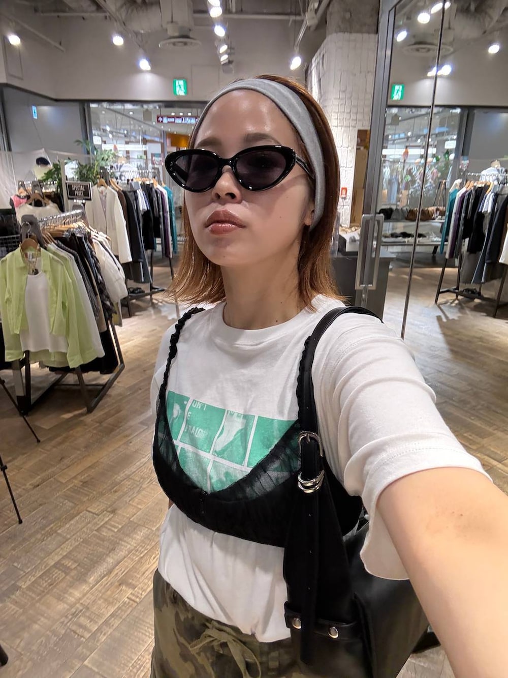ホワイト系のTシャツ/カットソー、ブラック系のパンプス、ブラック系のショルダーバッグを着用したレディースの夏コーディネートの3枚目の写真