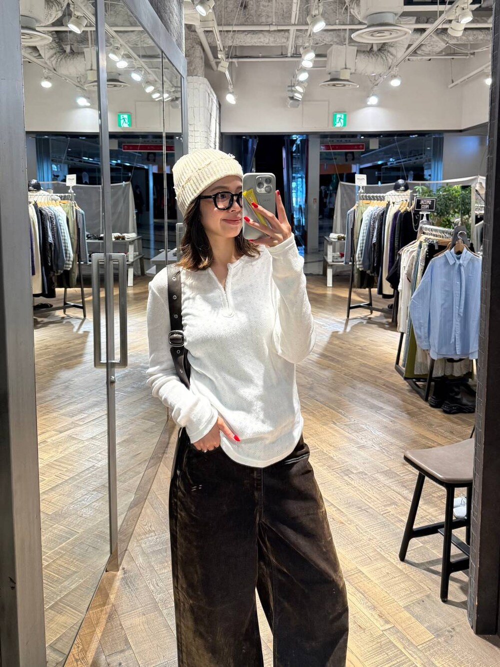 ブラウン系のショルダーバッグ、ホワイト系のTシャツ/カットソー、ブラウン系のデニムパンツを着用したレディースの秋コーディネートの2枚目の写真