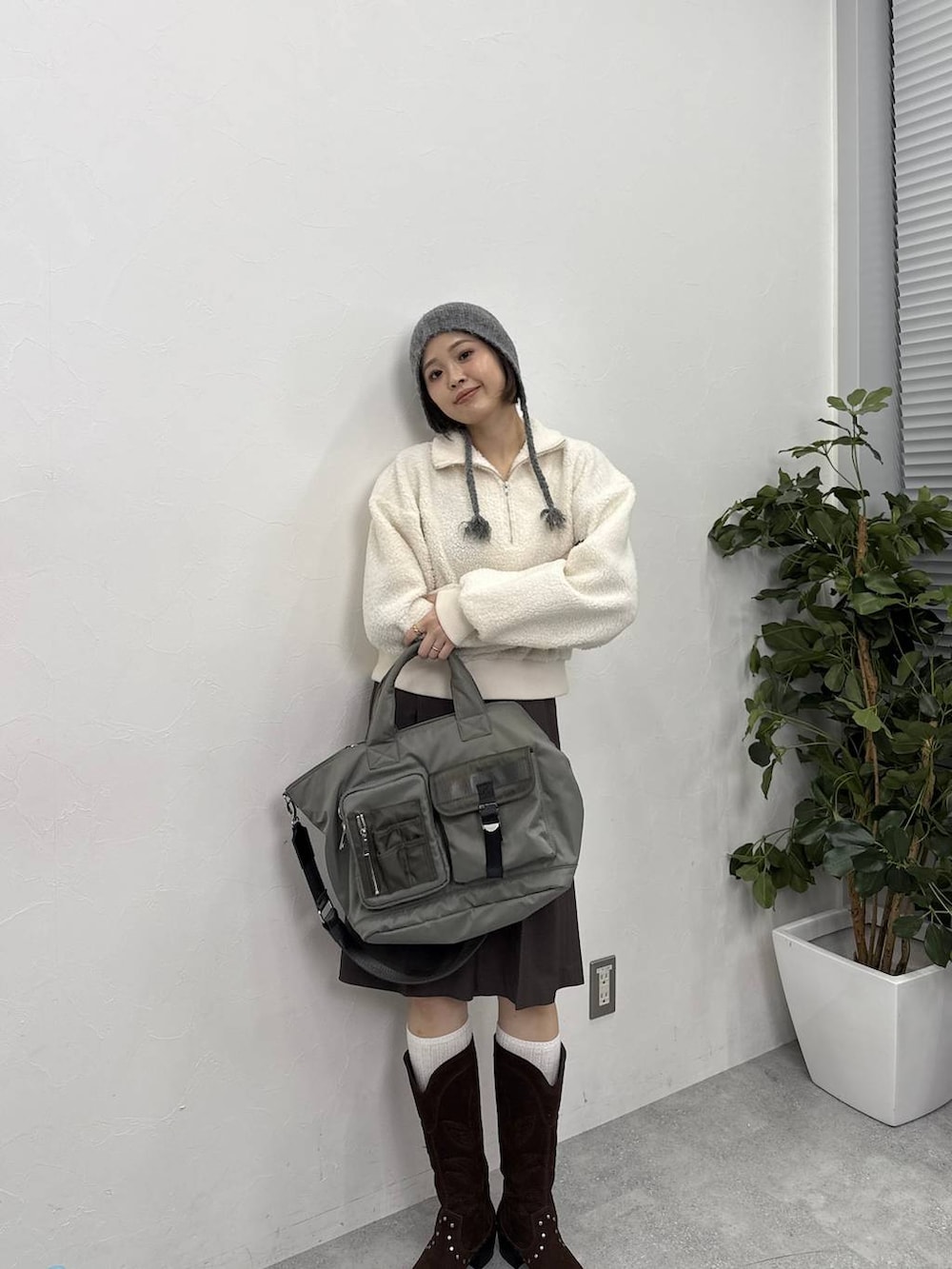 ホワイト系のスウェット、ブラウン系のブーツ、グリーン系のトートバッグを着用したレディースの冬コーディネートの2枚目の写真