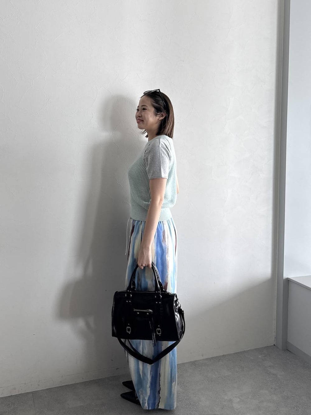 ブラック系のボストンバッグ、ブラック系のパンプス、グレー系のTシャツ/カットソーを着用したレディースの春コーディネートの2枚目の写真