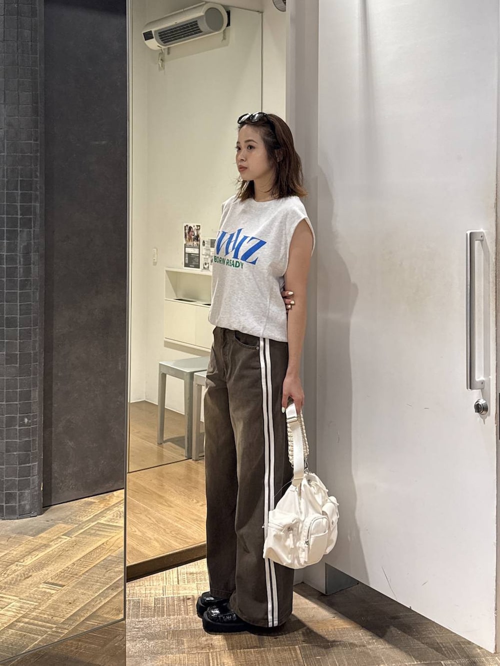 ホワイト系のショルダーバッグ、ブラック系のローファー、グレー系のTシャツ/カットソーを着用したレディースの夏コーディネートの2枚目の写真