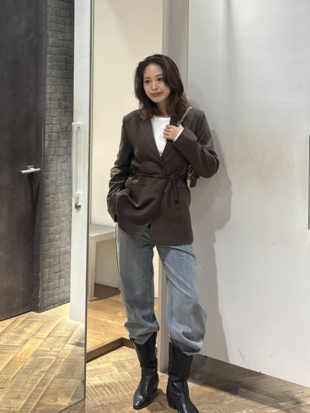 ブルー系のデニムパンツ、ブラウン系のテーラードジャケット、ホワイト系のTシャツ/カットソーを着用したレディースの秋コーディネートの3枚目の写真