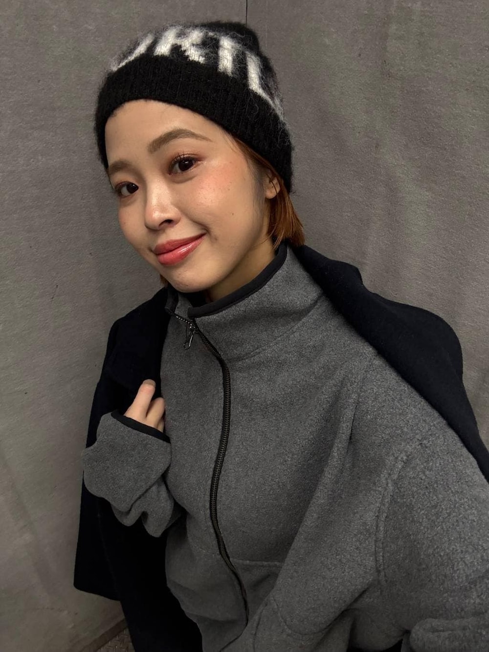 ブルー系のチェスターコート、グレー系のブルゾン、ブラック系のニットキャップ/ビーニーを着用したレディースの秋コーディネートの2枚目の写真