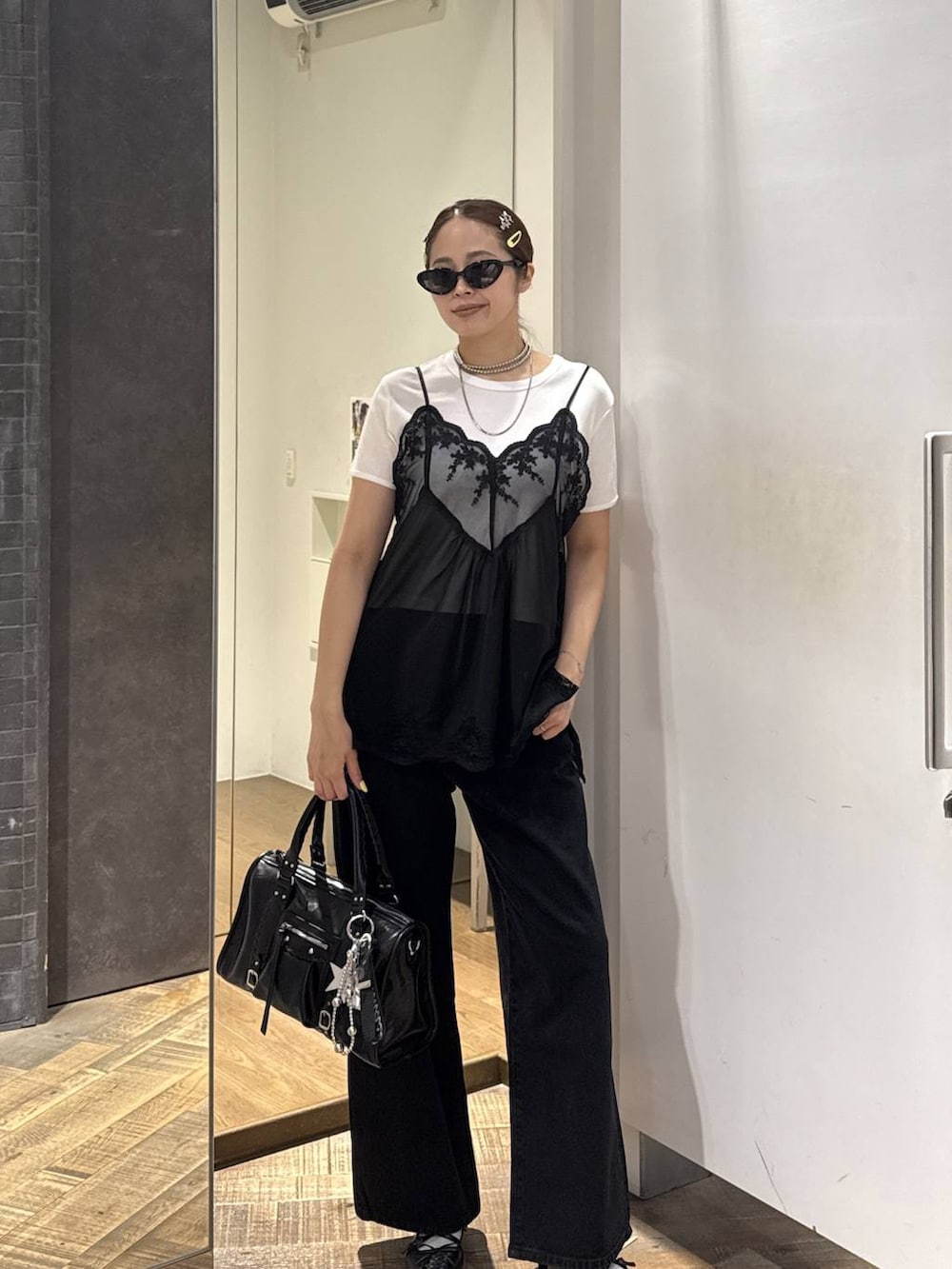 ブラック系のボストンバッグ、ブラック系のパンプス、ホワイト系のTシャツ/カットソーを着用したレディースの夏コーディネートの2枚目の写真
