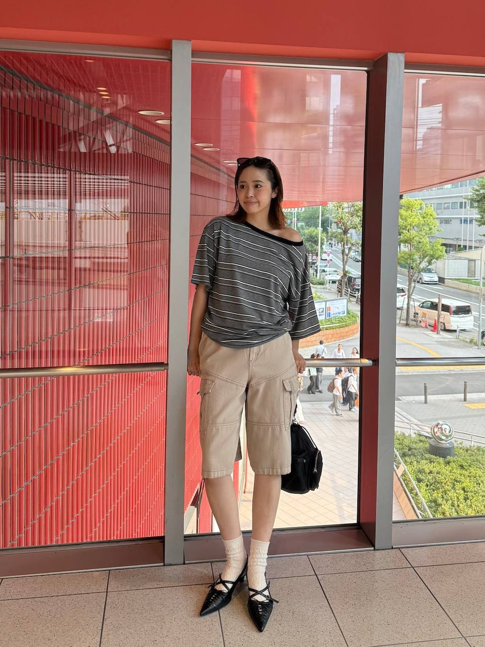 ブラック系のショルダーバッグ、グレー系のTシャツ/カットソー、ブラック系のパンプスを着用したレディースの夏コーディネートの2枚目の写真