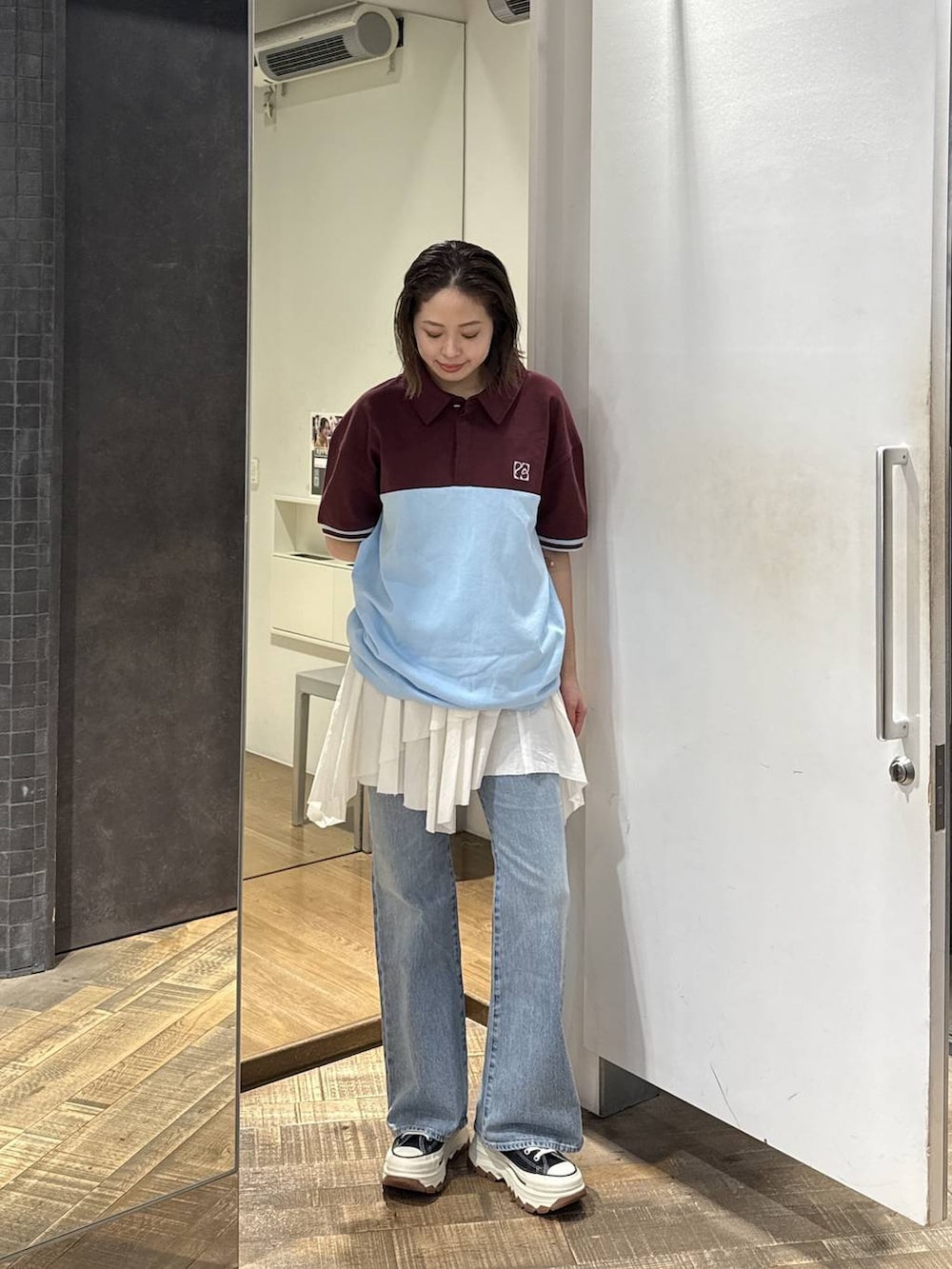 ブラック系のスニーカー、ブルー系のデニムパンツ、ホワイト系のスカートを着用したレディースの春コーディネートの3枚目の写真