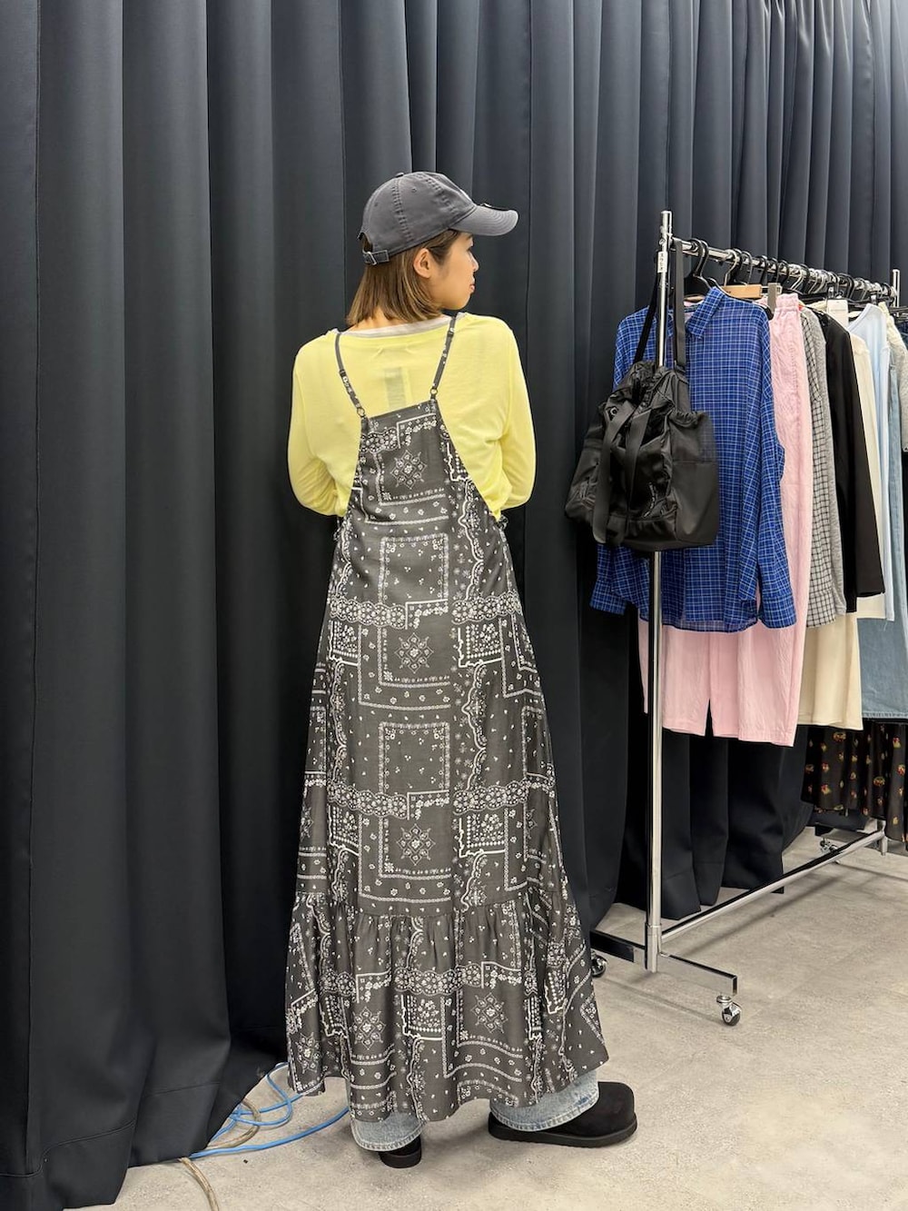 ブラック系のモカシン/デッキシューズ、ブラック系のワンピース、イエロー系のTシャツ/カットソーを着用したレディースの春コーディネートの2枚目の写真