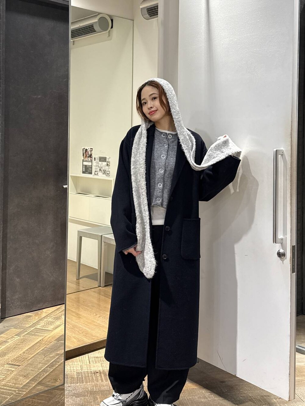 ブルー系のチェスターコート、ホワイト系のスニーカー、グレー系のカーディガン/ボレロを着用したレディースの秋コーディネートの4枚目の写真