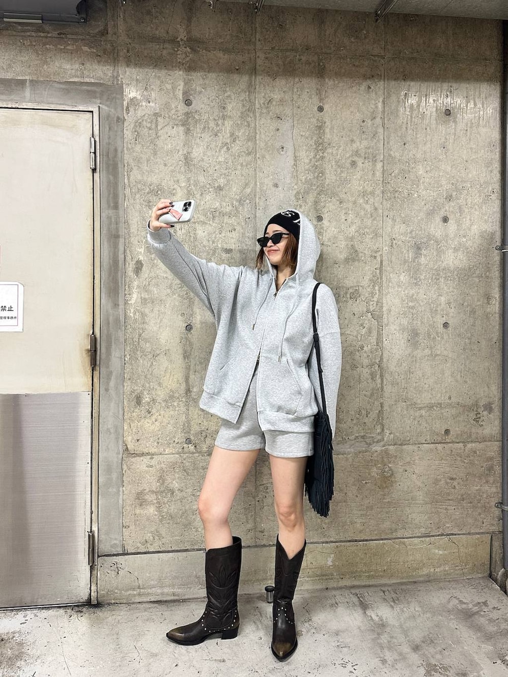 ブラック系のブーツ、グレー系のスウェットパンツ、グレー系のパーカーを着用したレディースの春コーディネートの2枚目の写真