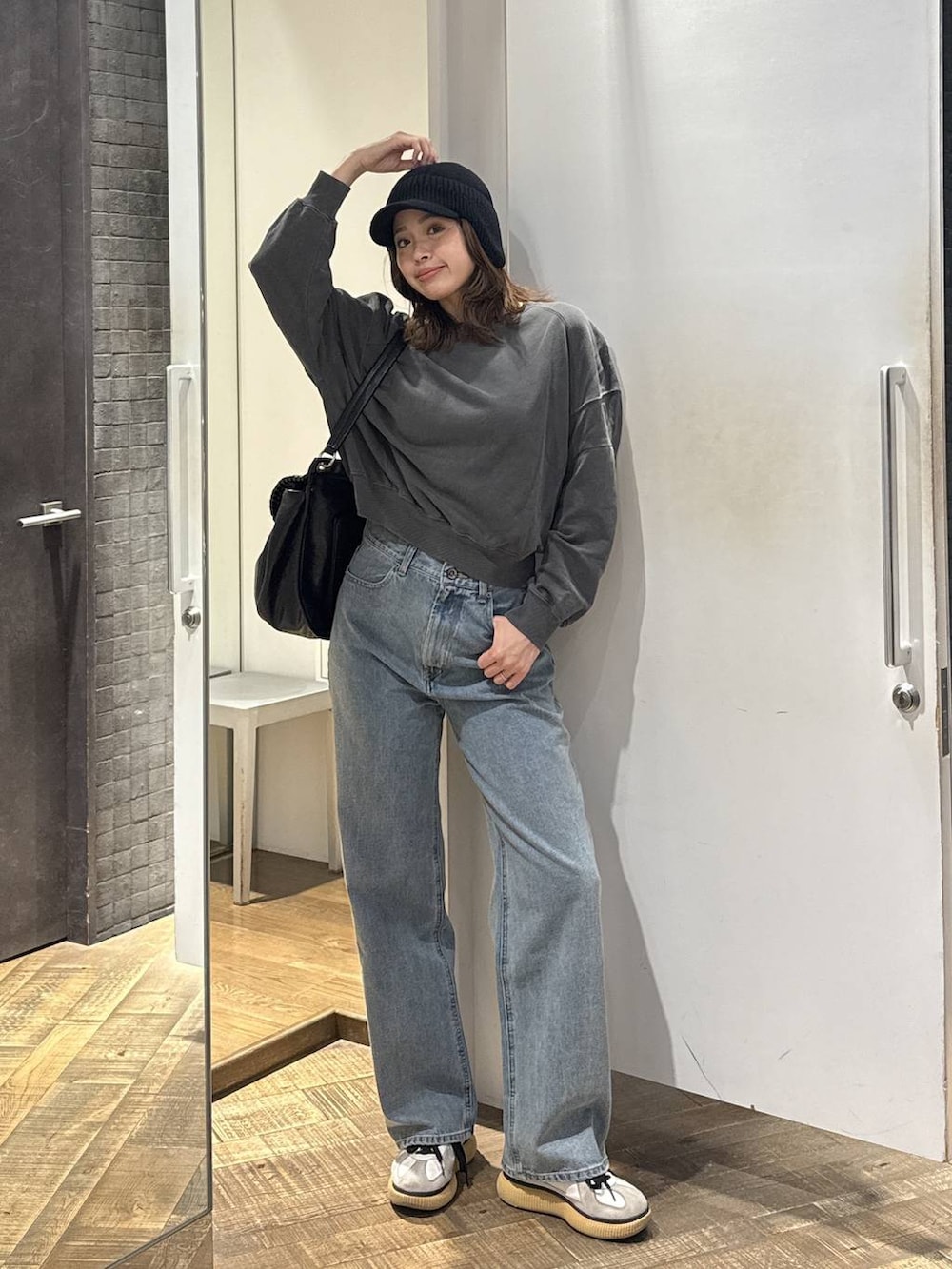 ブルー系のデニムパンツ、ブラック系のショルダーバッグ、グレー系のスウェットを着用したレディースの秋コーディネートの3枚目の写真