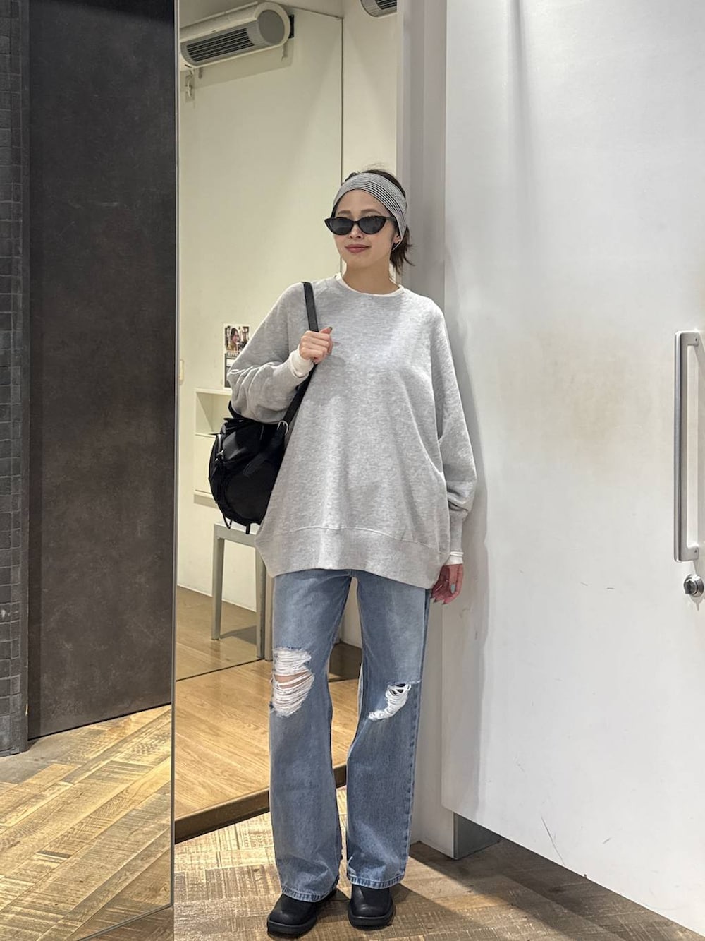 ブルー系のデニムパンツ、ブラック系のモカシン/デッキシューズ、グレー系のスウェットを着用したレディースの秋コーディネートの3枚目の写真