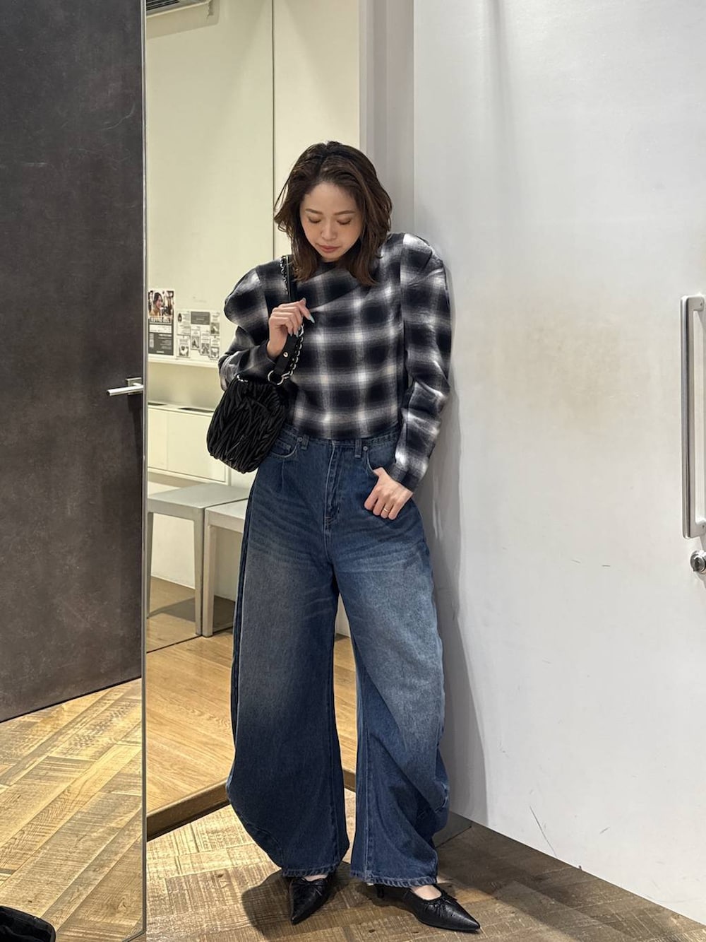 ブラック系のパンプス、ブラック系のショルダーバッグ、ブルー系のデニムパンツを着用したレディースの秋コーディネートの2枚目の写真