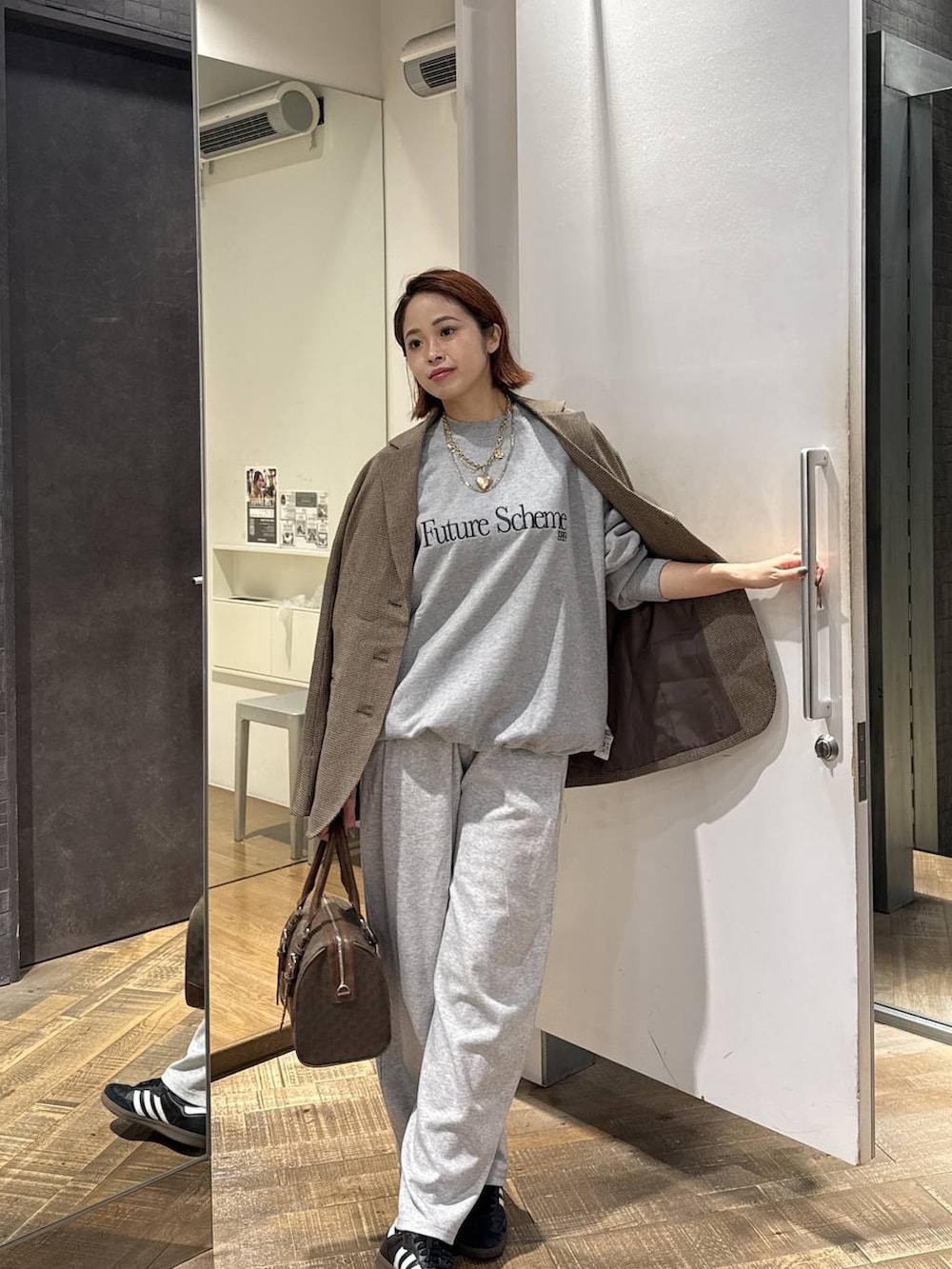 グリーン系のボストンバッグ、グレー系のスウェットパンツ、グレー系のスウェットを着用したレディースの秋コーディネートの4枚目の写真