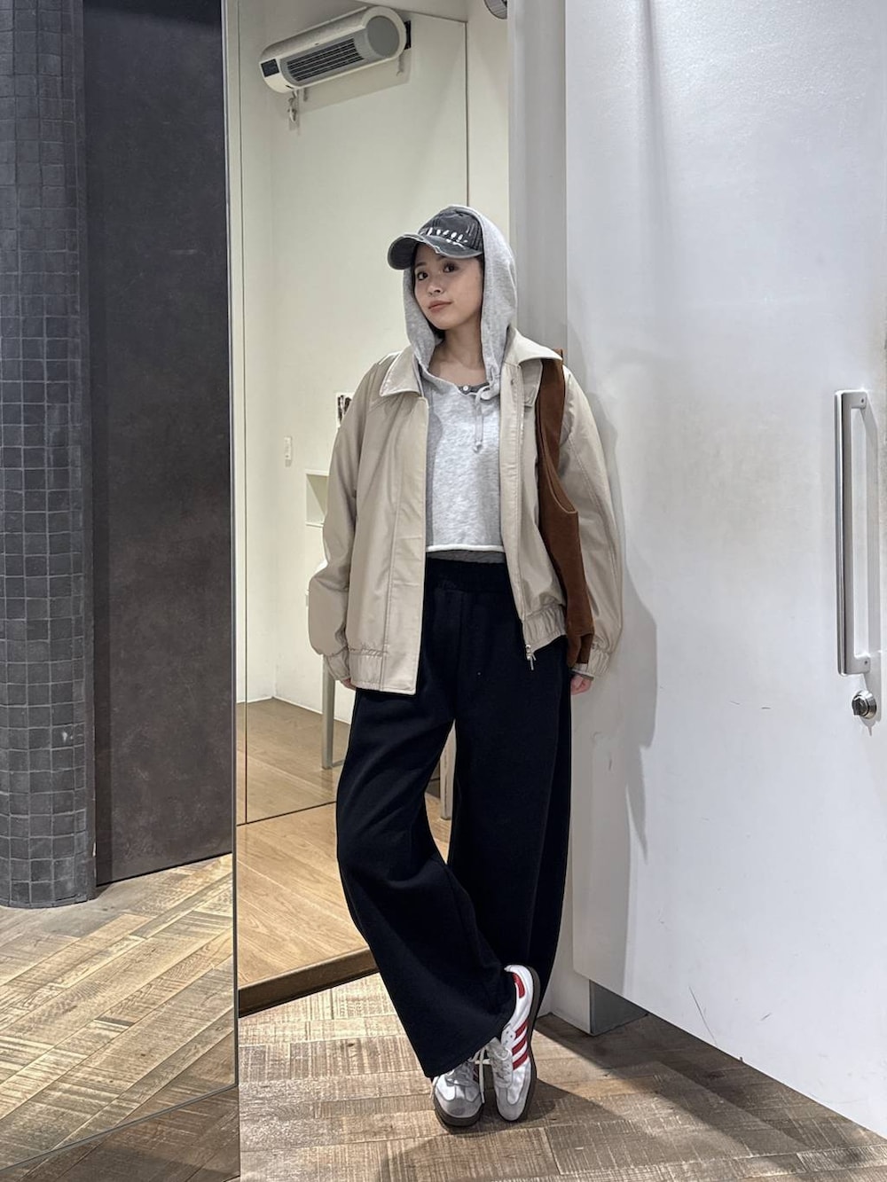 ブラウン系のトートバッグ、ベージュ系のブルゾン、グレー系のパーカーを着用したレディースの冬コーディネートの3枚目の写真