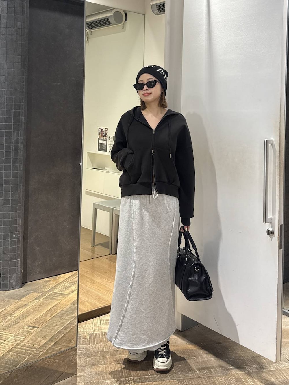 ブラック系のスニーカー、ブラック系のパーカー、ブラック系のトートバッグを着用したレディースの春コーディネートの2枚目の写真