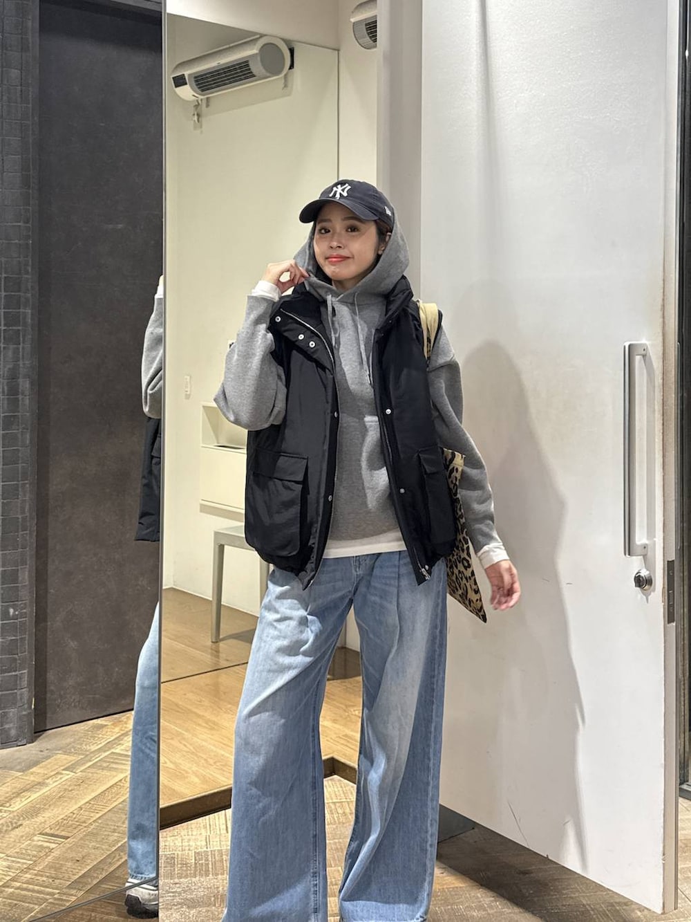 ブルー系のデニムパンツ、ベージュ系のトートバッグ、ホワイト系のスニーカーを着用したレディースの冬コーディネートの2枚目の写真