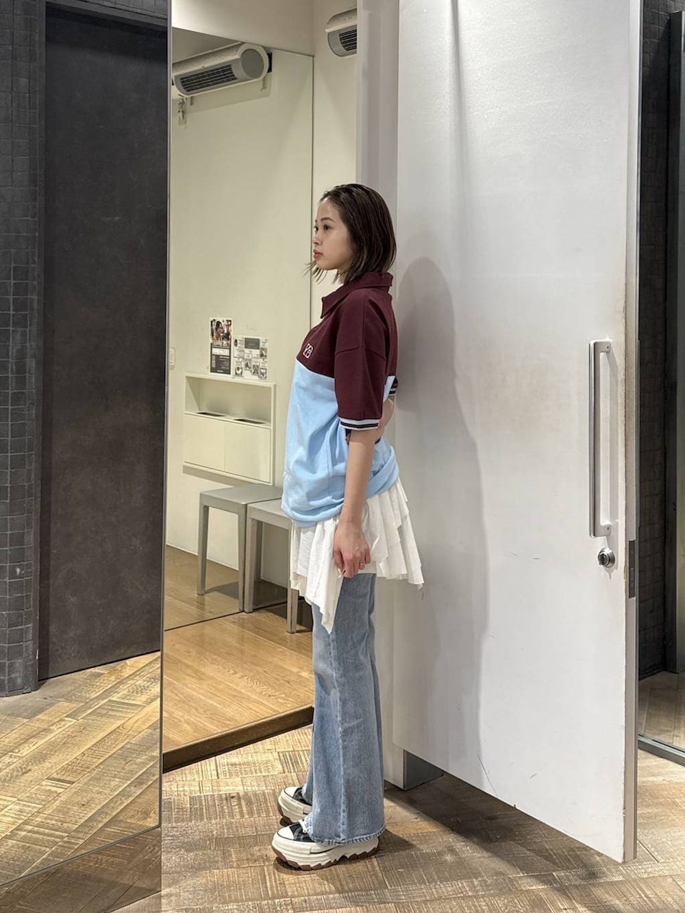 ブラック系のスニーカー、ブルー系のデニムパンツ、ホワイト系のスカートを着用したレディースの春コーディネートの2枚目の写真