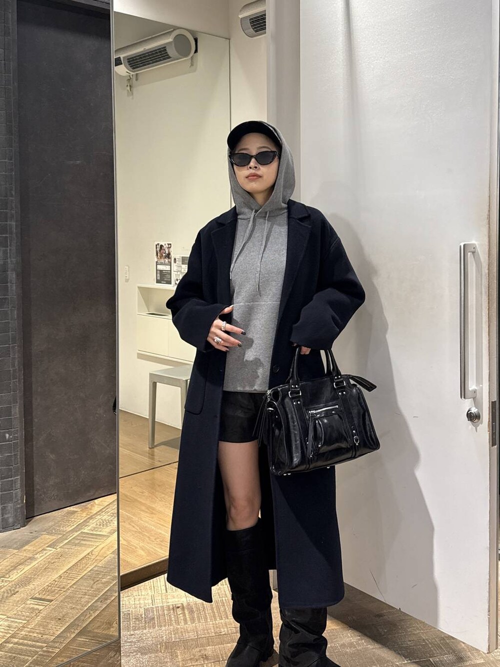 ブルー系のチェスターコート、ブラック系のブーツ、ブラック系のその他パンツを着用したレディースの冬コーディネートの2枚目の写真