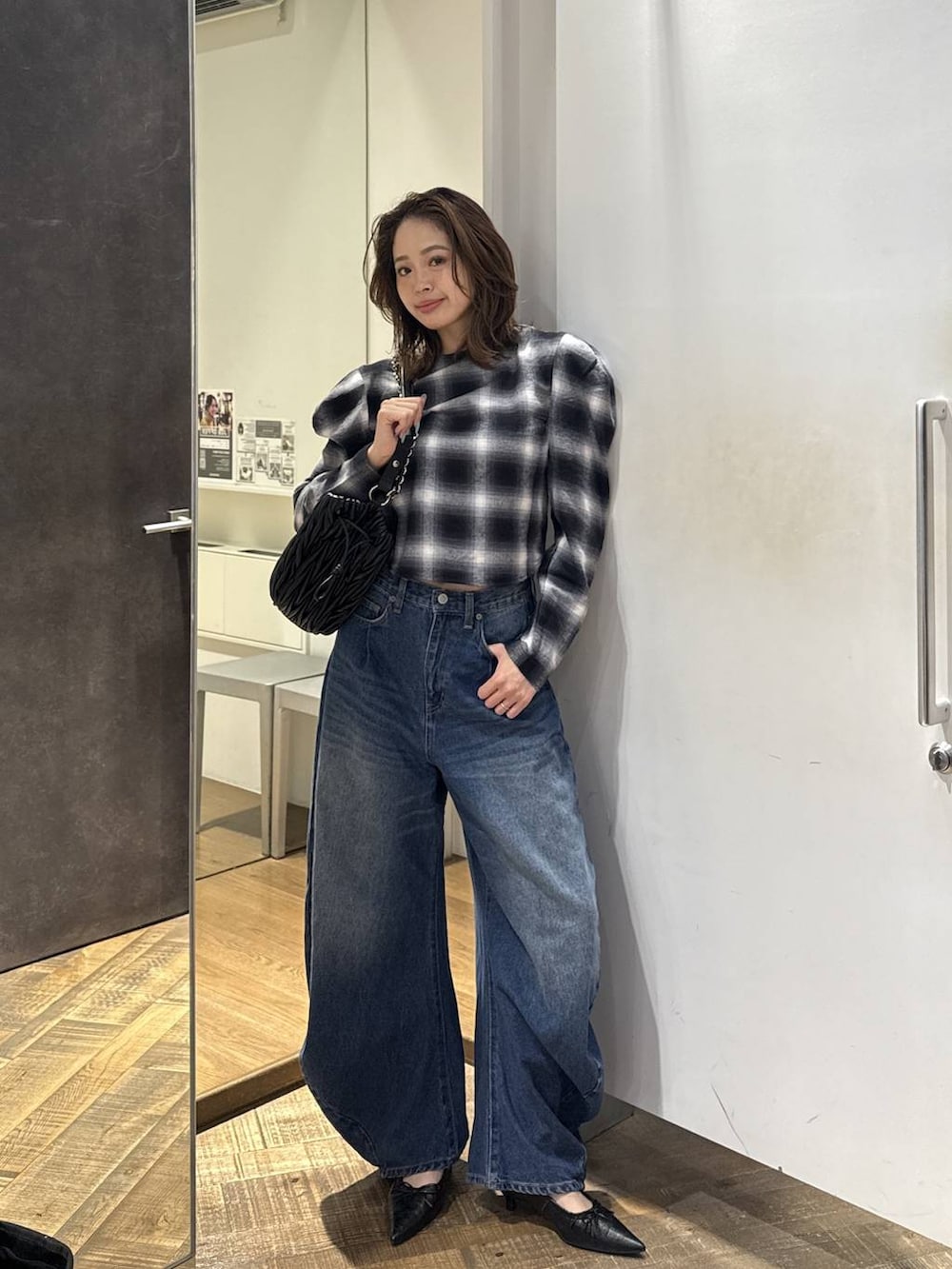ブラック系のパンプス、ブラック系のショルダーバッグ、ブルー系のデニムパンツを着用したレディースの秋コーディネートの3枚目の写真