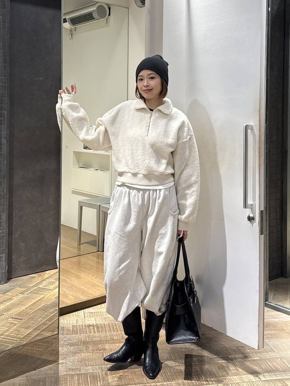 ブラック系のショルダーバッグ、ベージュ系のスウェットパンツ、ホワイト系のスウェットを着用したレディースの冬コーディネートの2枚目の写真