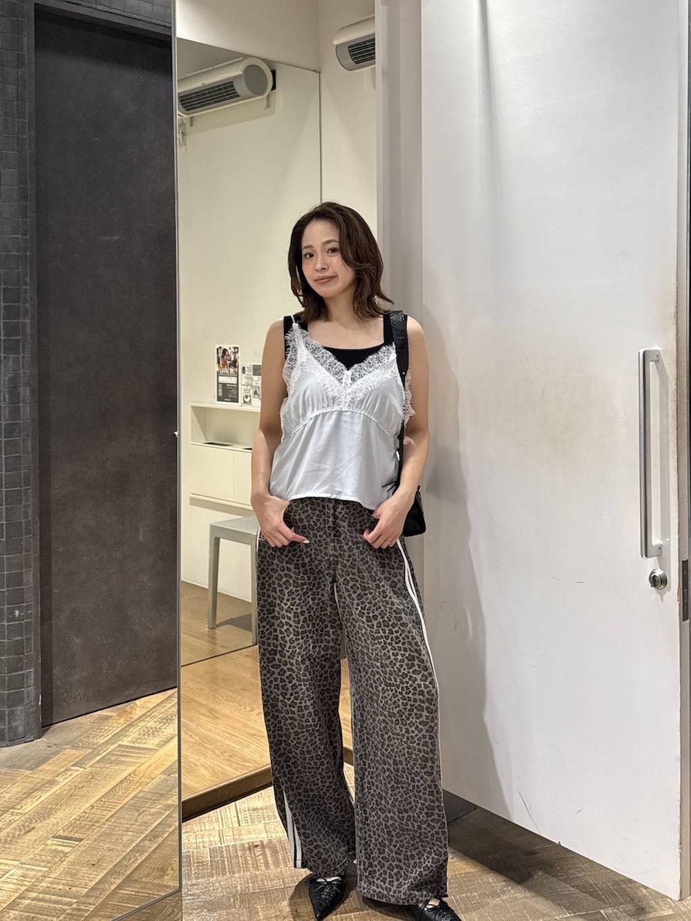 ホワイト系のキャミソール、ブラック系のタンクトップ、ブラック系のパンプスを着用したレディースの夏コーディネートの2枚目の写真