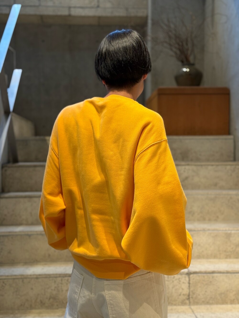 ベージュ系のデニムパンツ、オレンジ系のスウェットを着用したメンズの春コーディネートの2枚目の写真